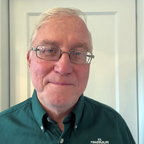 Head shot of man smiling and wearing a green USFWS uniform shirt.