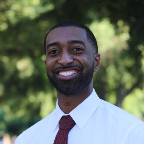 Nick Asfaha smiles in a portrait headshot