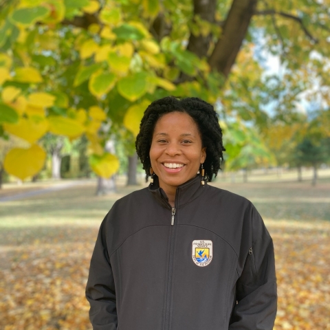 Shanice smiles with hands in pockets. She is wearing a black FWS zip up jacket. 