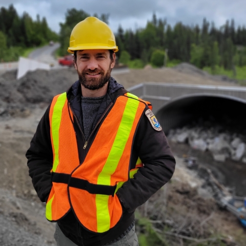 man in orange and hard hat by a culvert