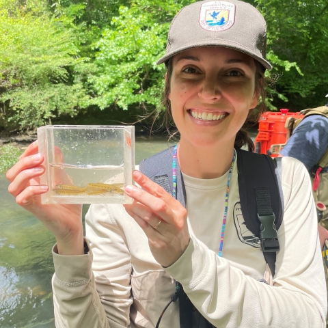 Jenna holding a viewing box with coal darters in it. Creek is in the background.