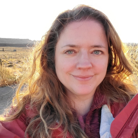 Photo of Jodie Delavan, USFWS employee in front of field at sunset