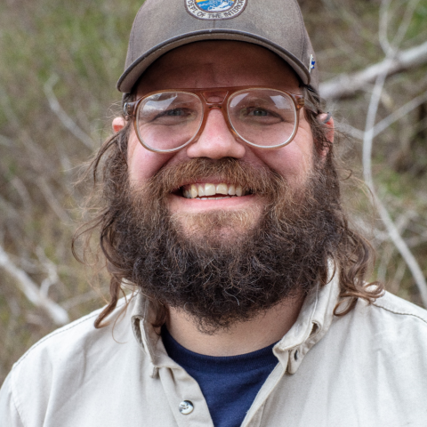 person with beard wearing glasses and a hat with USFWS logo