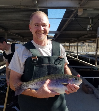 a man in waders hold a rainbow trout