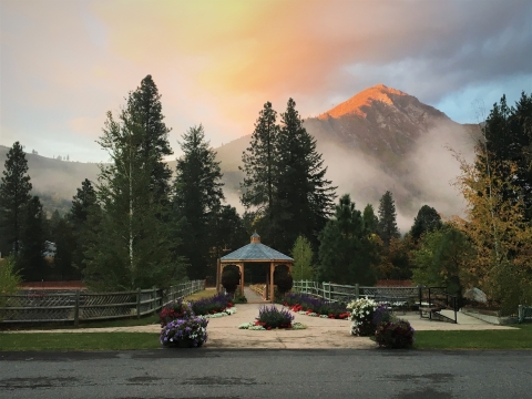 Hatchery gazebo and historic ponds with trees, fog, and mountain illuminated by early morning light in background