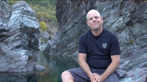 photo of a man with a stream and rocks in the background