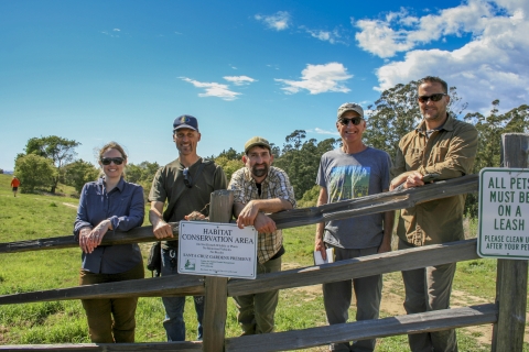 Five biologists posing for a photo by a fence