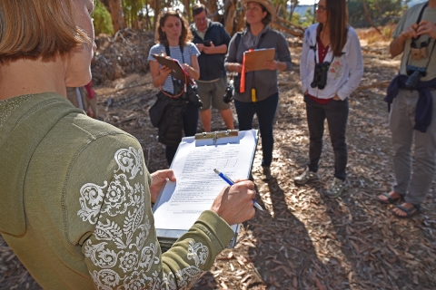 Woman with clipboard addresses group of people