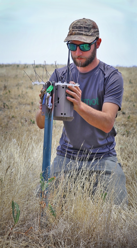 Man kneeling in field working on equipment