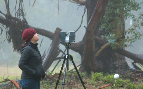 Woman stands next to equipment on tripod