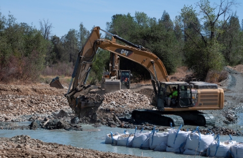 An excavator machine lifts and moves a pile of rocks