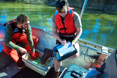 Two people on a boat record data