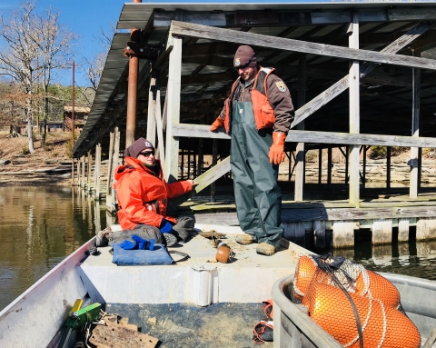 Two Service biologists wearing warm weather gear and personal flotation devices in their boat