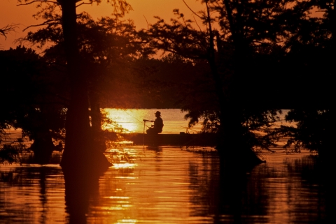 A person on a boat at sunset.