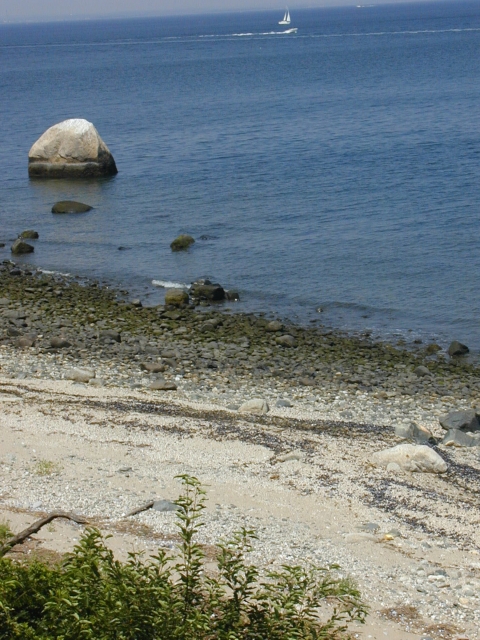 A large boulder sits in the bay offshore 