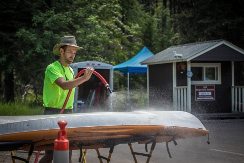 A man sprays off the bottom of a boat.