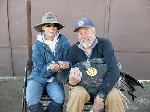 A man and a woman holding a large black bird