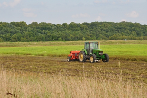 A tractor pulling a planter through a field.