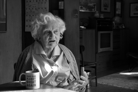 a black and white photo of an elderly woman sitting at a table