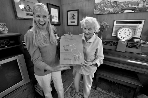 a black and white photo of two woman holding a piece of paper