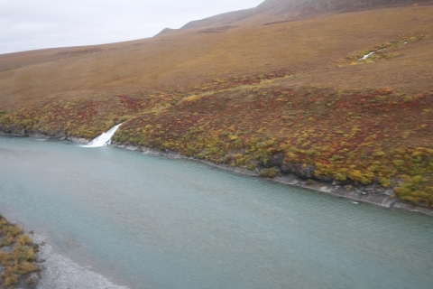 a waterfall coming out of a fall-colored hillside