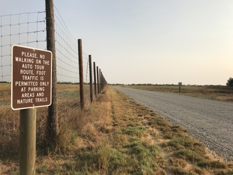 Gravel road with informational sign on shoulder.