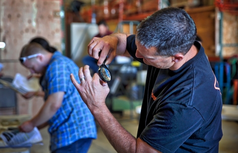 A man looks at a small fish under a magnifying glass