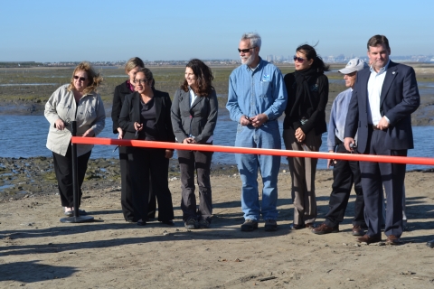 People standing side by side with a red ribbon in front of them ready to be cut