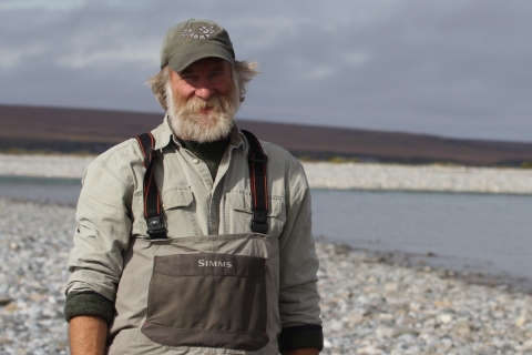 man in a hat and waders by a river