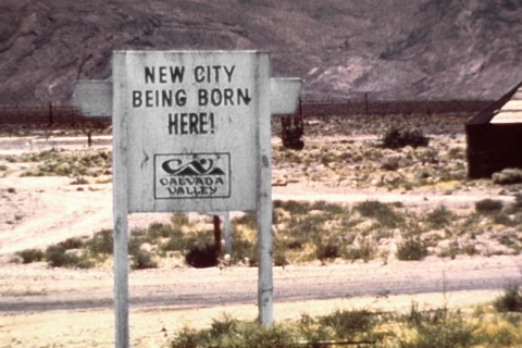 A sign infront of a lot with two buildings