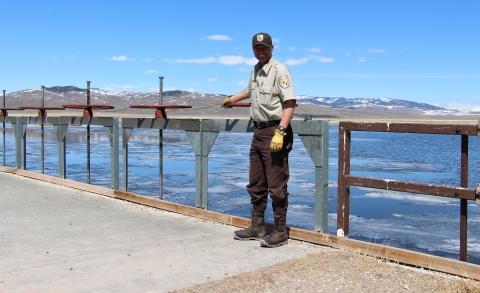 A man stands next to water control valves with water in the background.