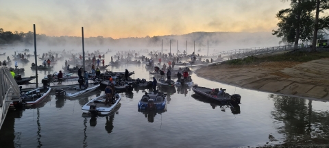 A foggy morning on the lake with lots of boats.