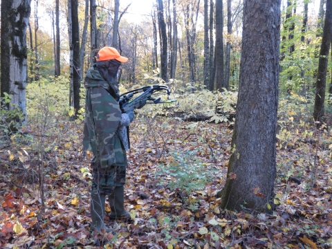 Archery hunter holding bow in woods