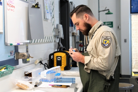 A man in a laboratory writes on a vial