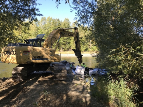 Excavator moving bags of soil