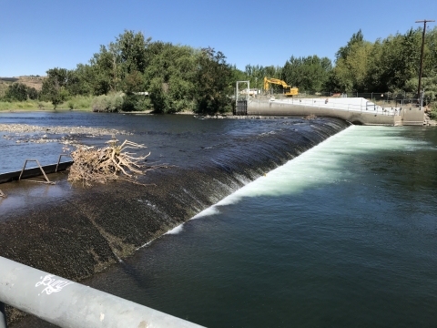 View of a low dam with water flowing over it.