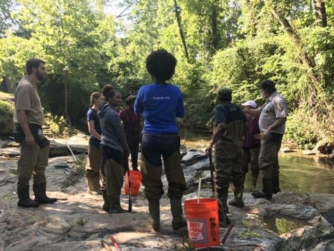 Group of community members stand in a circle planning their sampling efforts