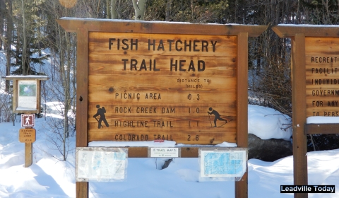 A wooden sign that indicates the distance from a trail head to certain points on the trail for snowshoeing and cross-country skiing. 