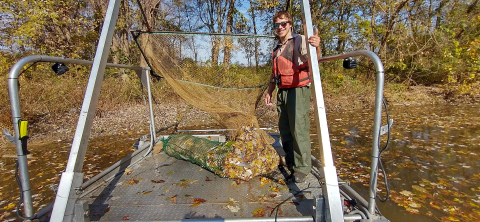 USFWS Staff standing on a boat with a dozer trawl net full of fish.