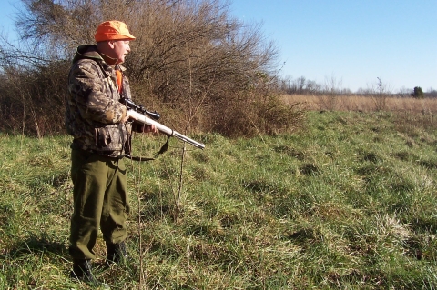 Gun hunter walking across field