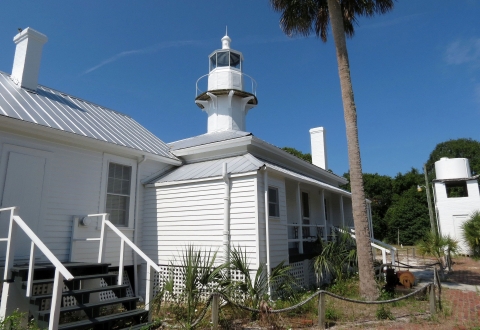 A short white lighthouse tower atop a single-level building