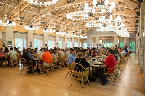 room set up with wooden tables and chairs and wooden beams in ceiling with lights