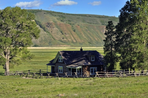 The historic Miller House at National Elk Refuge in Wyoming, with mountains behind it..