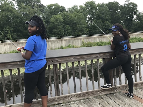 Zeta Phi Beta Sorority, Inc.members Kelsey Burks and Sierra Snyder fishing off a pier. 