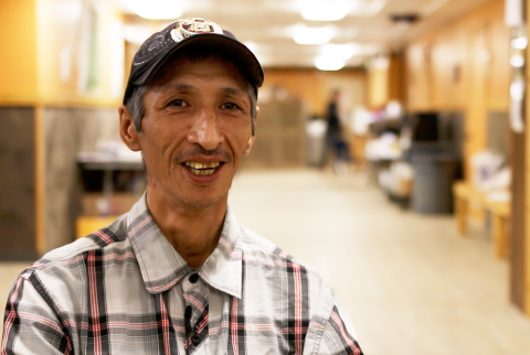 man in ball cap in white striped shirt looks at camera