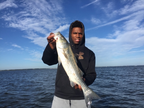  young man in boat holding fish 