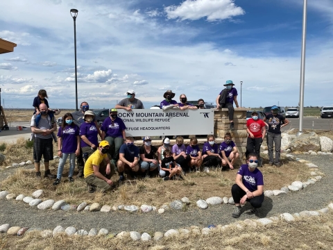 group around sign reading Rocky Mountain Arsenal National Wildlife Refuge Headquarters. All in masks