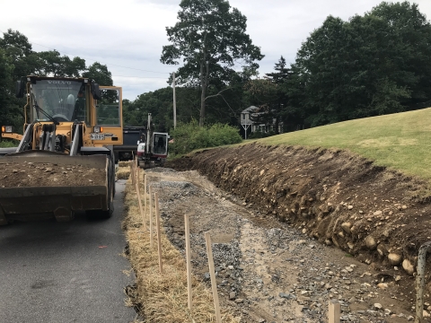 Heavy construction equipment moves dirt in preparation for construction of pedestrian trail.