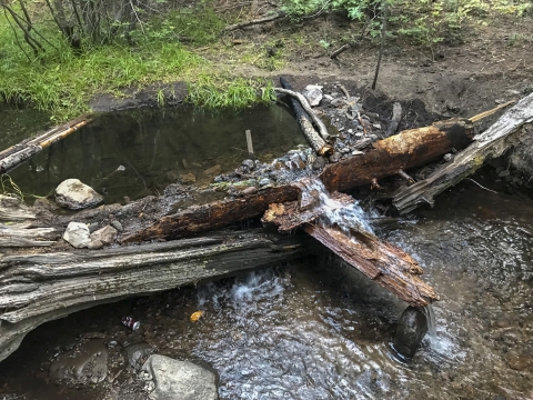 a stream with a dam of wood and rocks