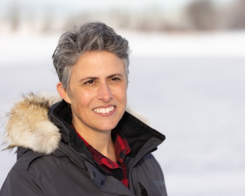 a woman in a coat with snow behind her